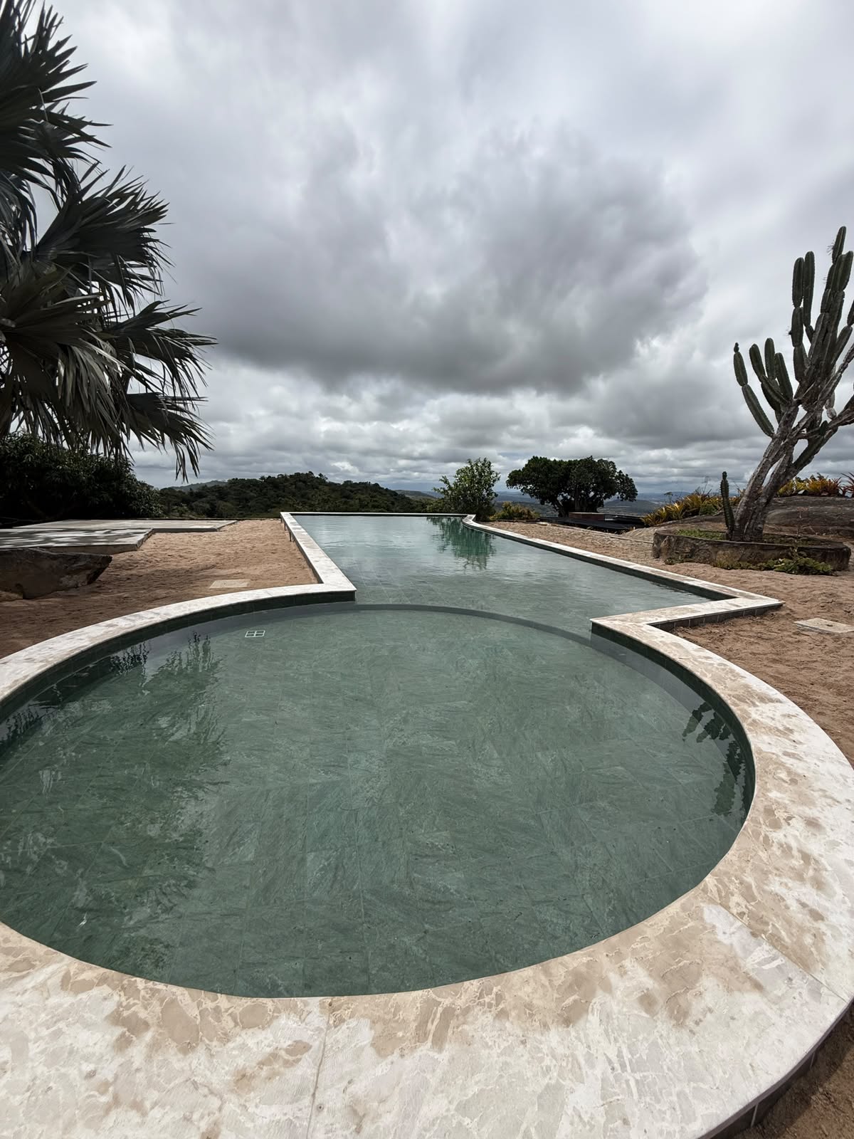 Piscina circular de borda infinita do Condomínio Reserva Serra Negra, com vista para as colinas